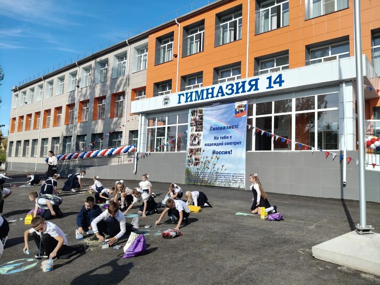 После линейки малыши выходят во двор и творят на асфальте: флаги, радуга, солнце и облака; одна девочка изобразила земной шар с фигуркой человека.